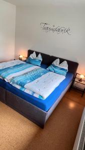 a large bed in a room with blue sheets and pillows at Ferienwohnung Margrit in Detern