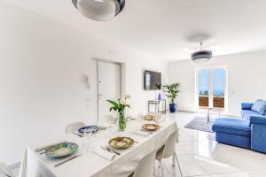 a white living room with a table and a blue couch at Villa Rusinella Minimalist Retreat with Sea Views by Feeling Italy in Massa Lubrense
