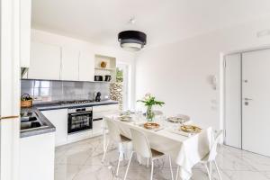 a white kitchen with a table with white chairs at Villa Rusinella Minimalist Retreat with Sea Views by Feeling Italy in Massa Lubrense +53 photos