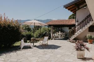 a patio with two chairs and an umbrella at Guest House Al Devesio in Rifreddo