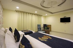 a hotel room with two beds and a flat screen tv at Hotel Grand Suites By D Capitol- New Delhi Airport in New Delhi