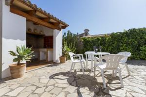 a patio with white chairs and a table on a patio at Villa Jaume in Pollença