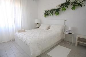 Maison Floria Locazione Turistica في بيسكارا: غرفة نوم بسرير ابيض عليها نبات