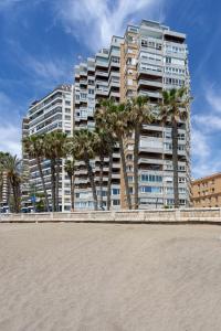 un edificio alto con palmeras delante en Malagueta Luz by Renthas en Málaga