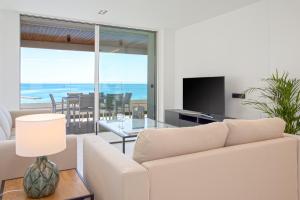 Sala de estar con sofá blanco y vistas al océano en Malagueta Luz by Renthas en Málaga