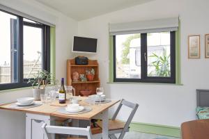 a dining room with a table and two windows at Puckaster Cove Cabin in Niton