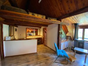 una sala de estar con techos de madera y sillas azules en Maison d’hôtes les Méans, en Méolans