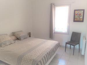 a bedroom with a bed and a chair and a window at Superbe Appartement FREJUS PLAGE in Fréjus