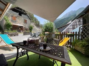 un patio con mesa y sillas en el césped en Maison d’hôtes les Méans, en Méolans