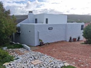 una casa blanca con un camino de piedra delante de ella en South Of Africa, en Agulhas