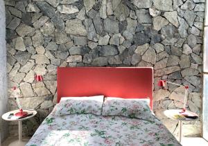 a bedroom with a red bed and a stone wall at Jauja in San Javier