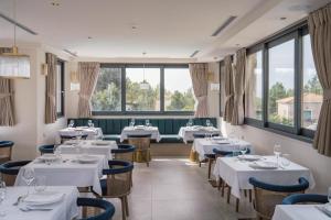um restaurante com mesas e cadeiras brancas e janelas em Celestial All Suites em Kefalonia