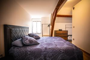 1 dormitorio con 1 cama con mantas y almohadas moradas en Gîte Chez Louis le Tonnelier Suite First en Le Mesnil-sur-Oger