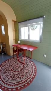 una stanza con un tavolo rosso e un tappeto di fronte a una finestra di Private small studio in Costa de Caparica a Costa da Caparica