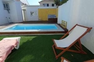 a chair and a swimming pool in a backyard at Private small studio in Costa de Caparica in Costa da Caparica
