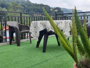 een tafel en stoelen op een balkon met groen gras bij The Sangam Homestay in Kalimpong