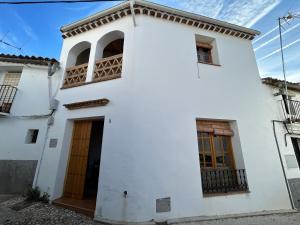 Casa blanca con puertas y ventanas marrones en Campanario 3 en Alájar