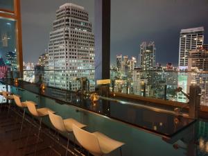 曼谷的住宿－曼谷索拉利亚西铁饭店，阳台配有椅子,晚上则享有城市天际线