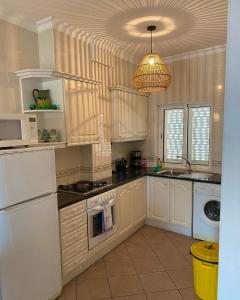 a kitchen with white cabinets and a white refrigerator at Nascer do Sol in Luz