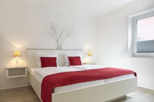 a white bedroom with a large bed with red pillows at Sea Captain - Ferienwohnungen in Büsum