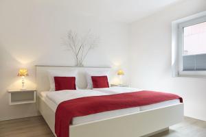 ein weißes Schlafzimmer mit einem großen Bett mit roten Kissen in der Unterkunft Sea Captain - Ferienwohnungen in Büsum