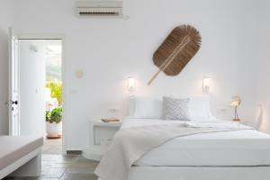 プラティスヤロス・シフノスにあるGerani Suites Sifnosの白いベッドルーム(ベッド1台、壁にほうき付)