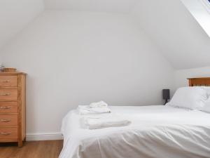 a bedroom with a white bed and a wooden dresser at Roe Cottage - Uk33490 in Hadleigh