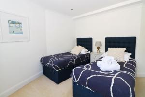 two beds in a room with white walls at APARTMENT BY THE BEACH The Foxcove in St Merryn