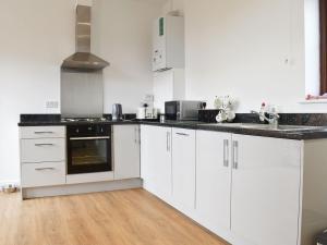 una cocina con armarios blancos y encimeras negras en Roe Cottage - Uk33490, en Hadleigh