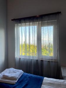 Schlafzimmer mit einem Bett und einem Fenster mit Vorhängen in der Unterkunft Byurakan Guesthouse & Cottage in Byurakan