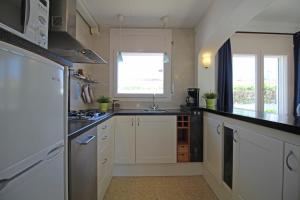 エンプリアブラバにあるApart-rent Casa Montseny 0119の白いキャビネット、シンク、窓付きのキッチン
