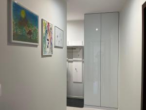 a hallway with paintings on the wall and a glass door at Apartament Esensja II in Szklarska Poręba