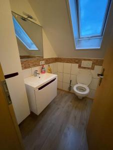 a bathroom with a sink and a toilet with a window at Ferienwohnung Anna in Hoppstädten-Weiersbach