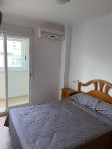 Schlafzimmer mit einem Bett, einem Fenster und einer Tür in der Unterkunft Apartamento en playa de Cullera in Cullera