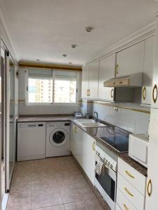 eine Küche mit weißen Schränken, einer Waschmaschine und einem Trockner in der Unterkunft Apartamento en playa de Cullera in Cullera