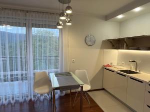 Apartament Esensja II في شكلارسكا بوريبا: مطبخ مع طاولة وكراسي ونافذة