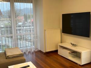 a living room with a flat screen tv and a couch at Apartament Esensja II in Szklarska Poręba