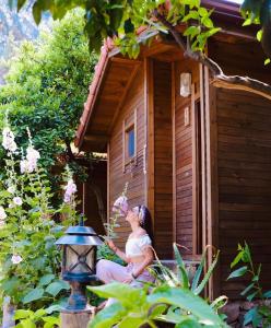 a woman sitting outside of a wooden house at Sheriff, Olympos in Kumluca