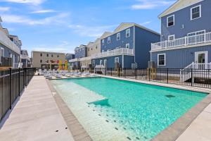 a swimming pool with chairs and buildings in the background at Oasis by Seaport Stays in Wildwood