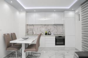 a kitchen with white cabinets and a table and chairs at Apartman Viktor in Igalo