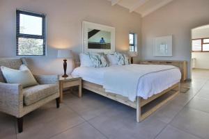 a bedroom with a large bed and a chair at Shorebreak in Southbroom