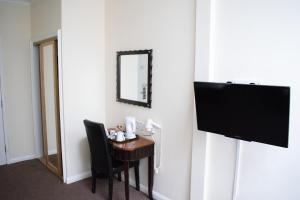 um quarto com uma secretária, uma televisão e uma cadeira em Britannia Hotel City Centre Manchester em Manchester