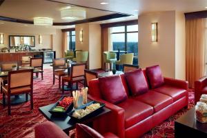 ein Wohnzimmer mit einem roten Sofa sowie Tischen und Stühlen in der Unterkunft Marriott Bloomington Normal Hotel and Conference Center in Bloomington