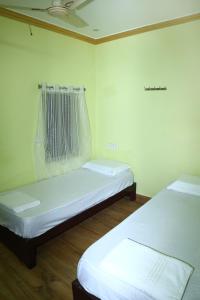 2 letti in una camera con pareti bianche e pavimenti in legno di SPOT ON V Guest Inn a Tenāli
