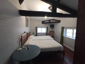 a bedroom with a bed and a table and two windows at Hotel Ormazabal in Bergara