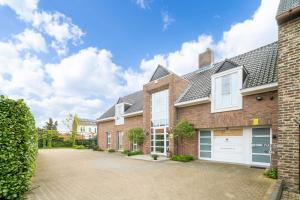 a large brick house with white garage doors at Maas&Mechelen B&B Massage & Wellness in Maasmechelen