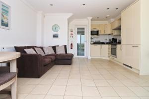 a living room with a brown couch and a kitchen at SEA VIEWS, beachside apartment with balcony in Saint Merryn