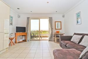 een woonkamer met een bank en een televisie bij SEA VIEWS, beachside apartment with balcony in Saint Merryn