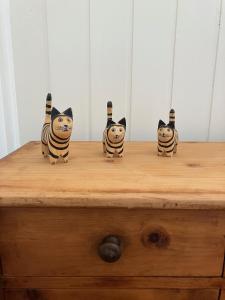 four figurines of cats sitting on a wooden dresser at La Lanterne in Sierre