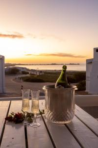 una bottiglia di vino in un secchio su un tavolo con bicchieri di Flamink Beach View Cottage in Paternoster a Paternoster